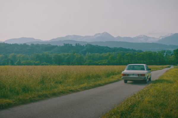 Une voiture disparaît au loin sur une route.