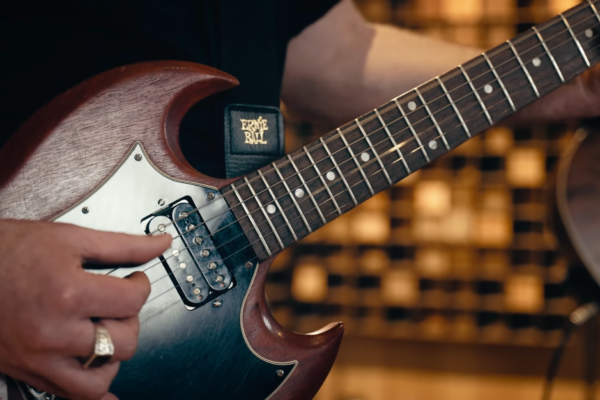 Main de guitariste jouant sur une guitare électrique pendant une captation live.